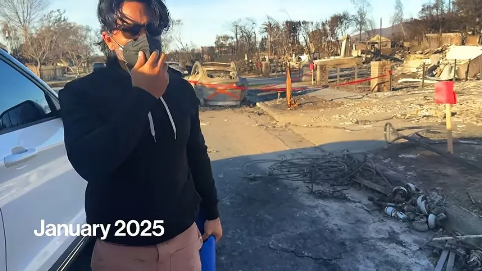 Una persona frente a un auto quemado con el rótulo «January 2025» abajo a la izquierda