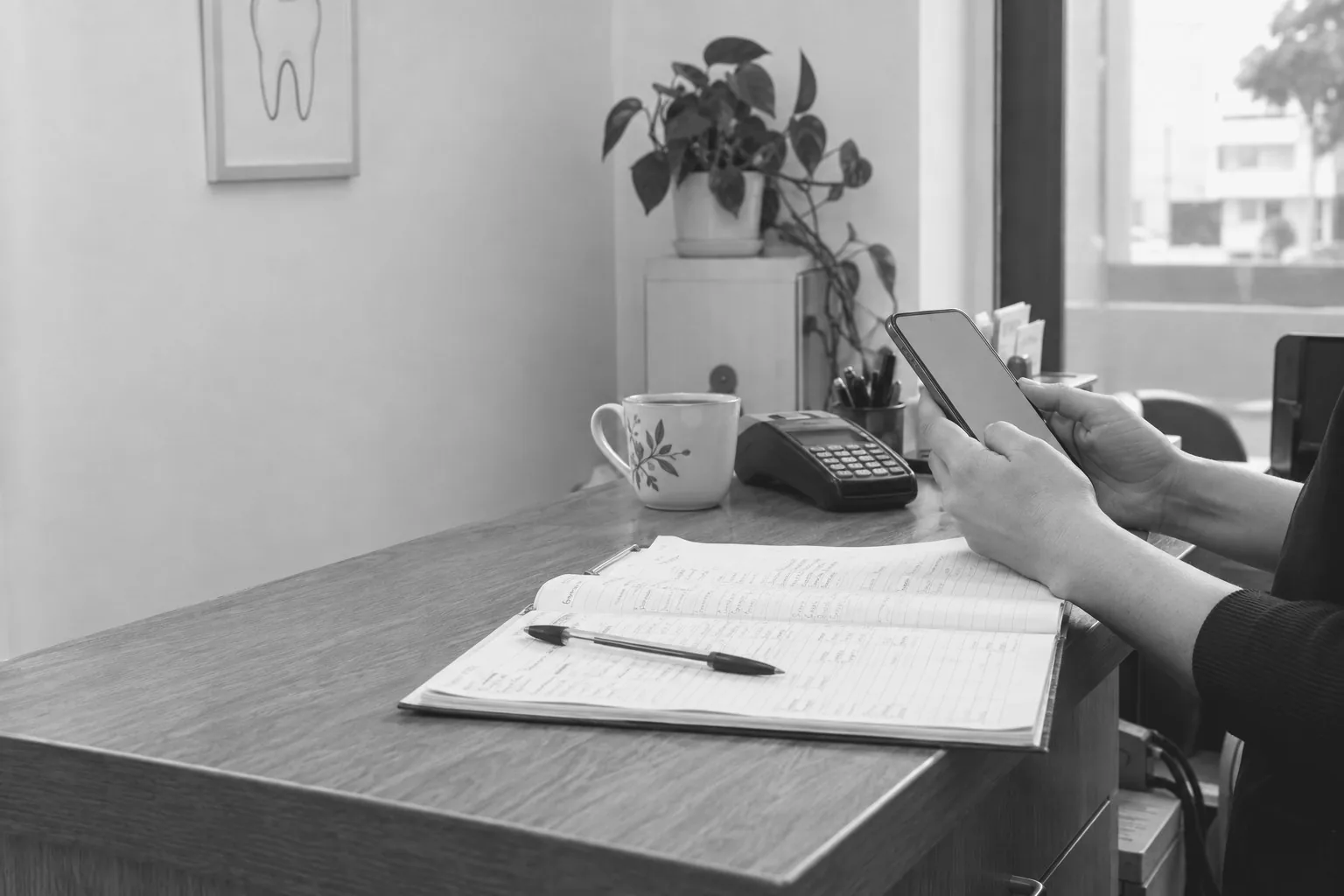 Manos con un celular sobre el mostrador de una recepción